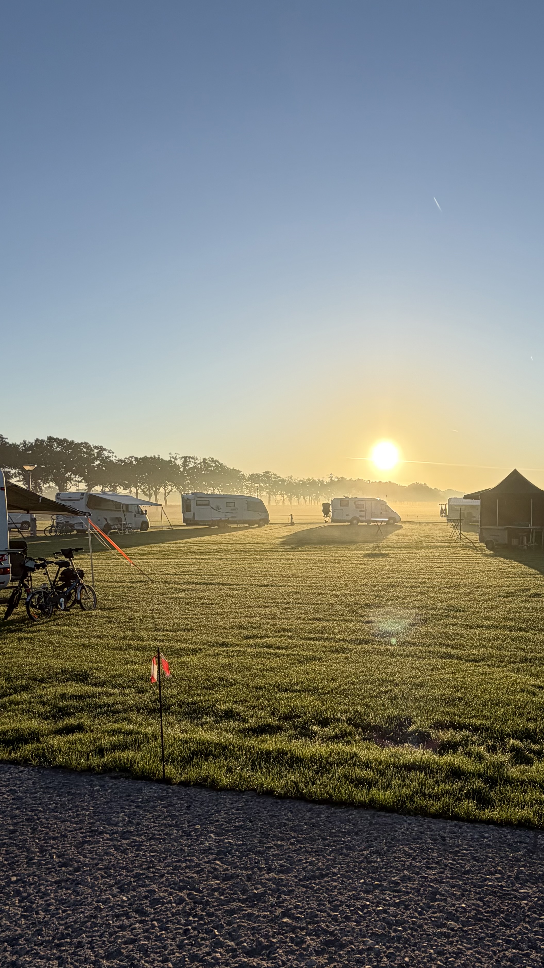 Campers op het groene terrein van Camperpark Deurne in de ochtendzon